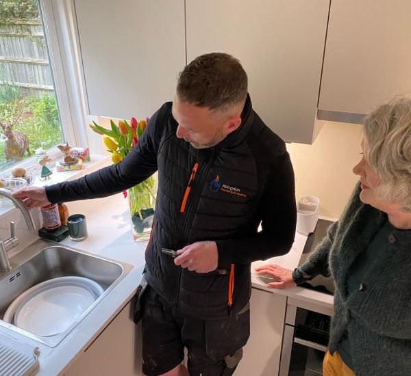 A man and a woman checking a water tap in a kitchen